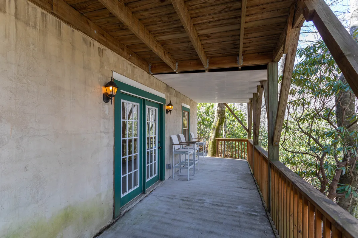 The exterior of Timber Lodge features double French doors opening onto a charming outdoor seating area beneath wooden beams. The space is ideal for enjoying morning coffee, listening to the sounds of the forest, or hosting small gatherings as the sun rises or sets.