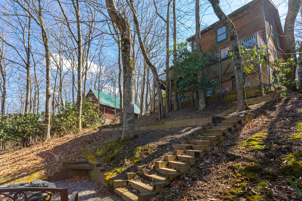 This image features the wooden cabin nestled among tall trees, with a staircase leading up to the deck, surrounded by the natural beauty of the High Country. The peaceful exterior invites families to imagine outdoor gatherings and the adventure that awaits just beyond the doorstep.