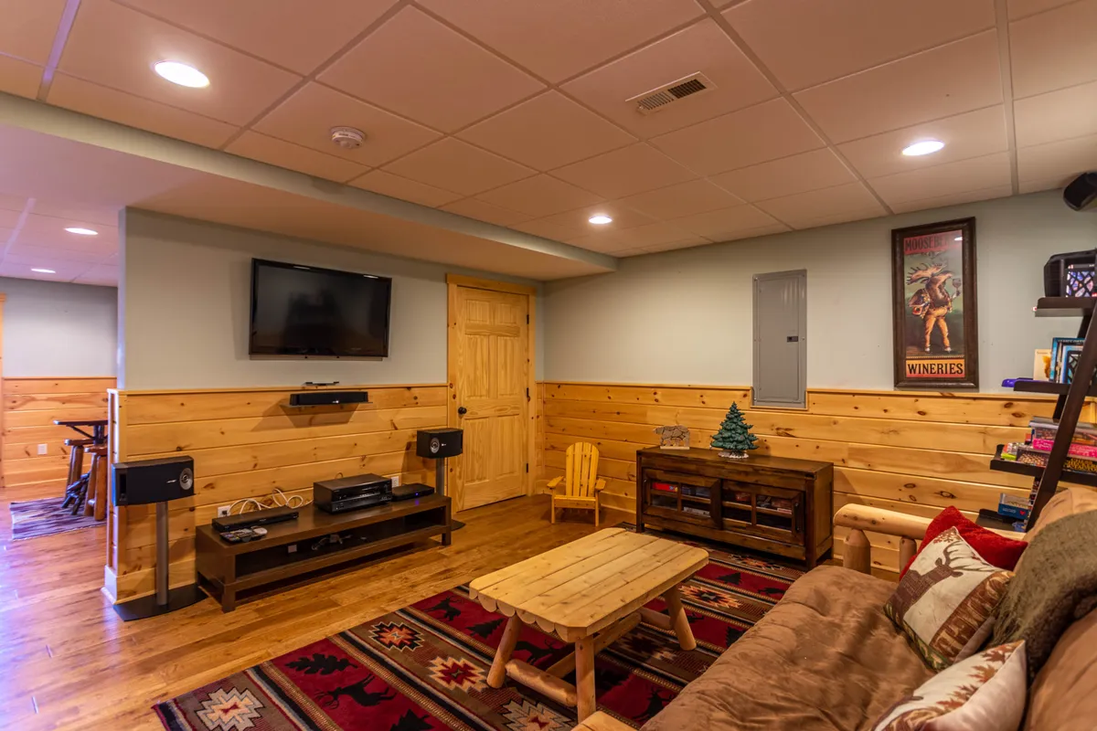 A cozy, relaxed living area with a sofa adorned with pillows, a wooden coffee table, a television, and decorative wall art. The room offers a comfortable spot for watching movies, playing games, or simply sharing stories with friends and family.