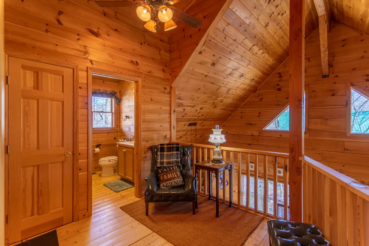 A sitting area with a plaid armchair beside a lamp, set against wood-paneled walls. The cozy corner is ideal for enjoying morning coffee, reading, or savoring a quiet moment. The soft lighting creates an inviting, tranquil mood.